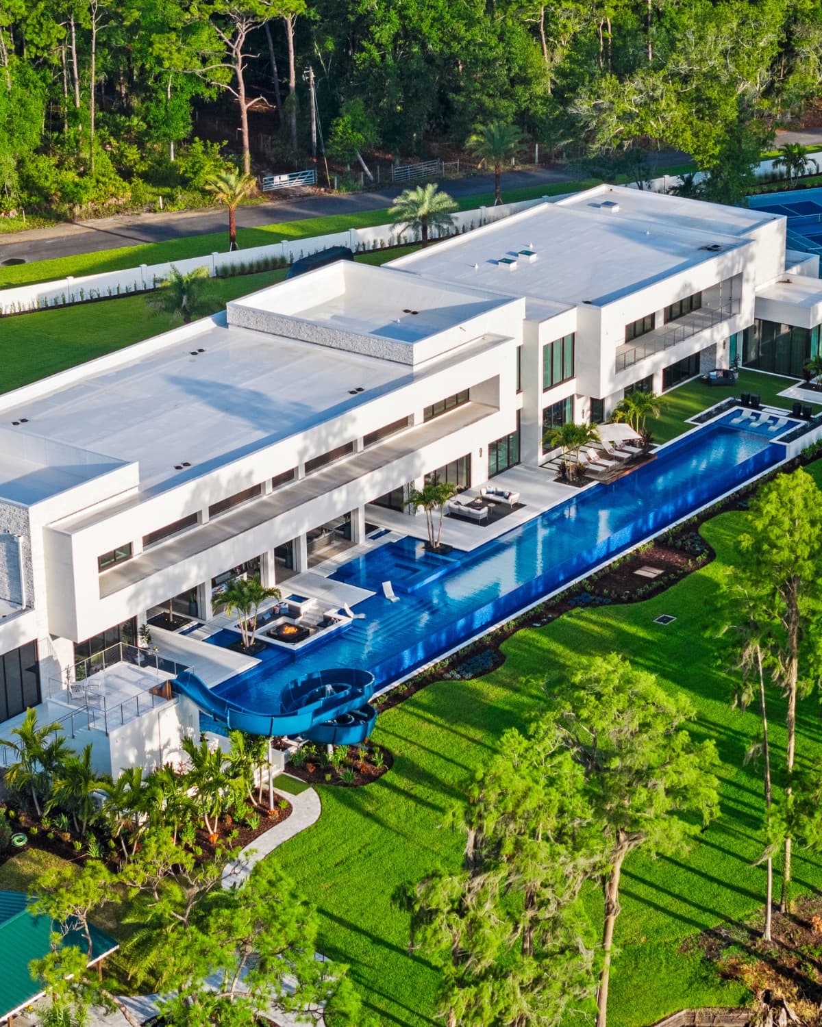 Luxury estate at night: illuminated pool, waterfall feature, dramatic landscape lighting