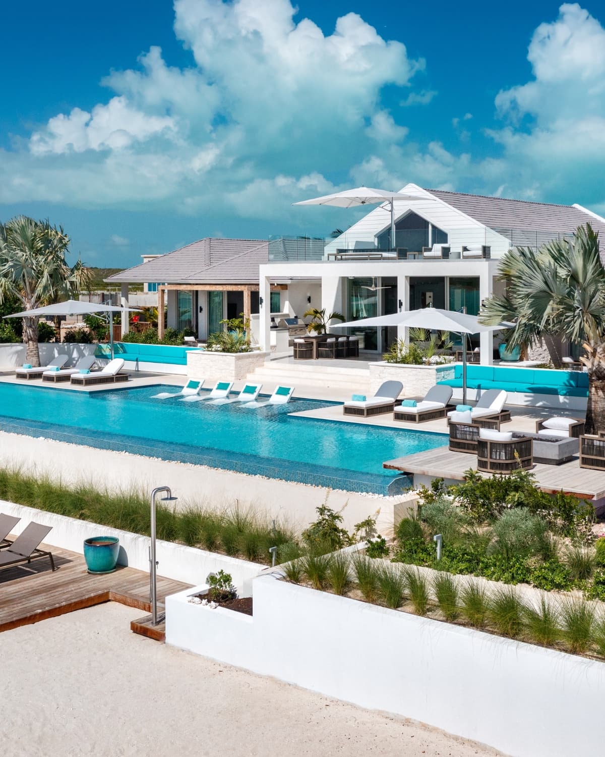 Eye-level view of a Caribbean luxury villa: infinity pool, loungers, dramatic sky