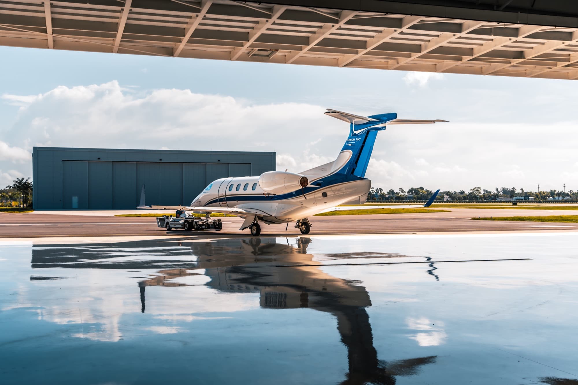Private jet on the ramp mirrored on the wet apron outside the hangar